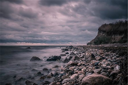 simsearch:6113-08947383,k - Tranquil rocks on ocean beach below stormy, overcast clouds, Bisserup, Denmark Stock Photo - Premium Royalty-Free, Code: 6113-08947387