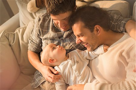 View from above male gay parents cuddling with cute baby son on sofa Foto de stock - Sin royalties Premium, Código: 6113-08947308