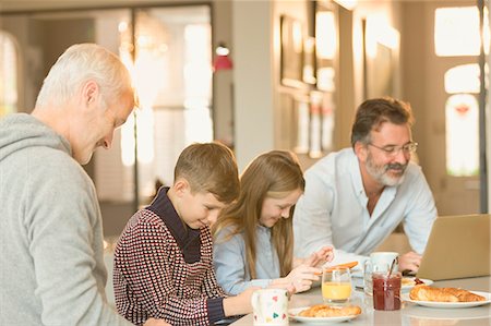 Male gay parents and children eating breakfast and using laptop and digital tablet at kitchen counter Stock Photo - Premium Royalty-Free, Code: 6113-08947329