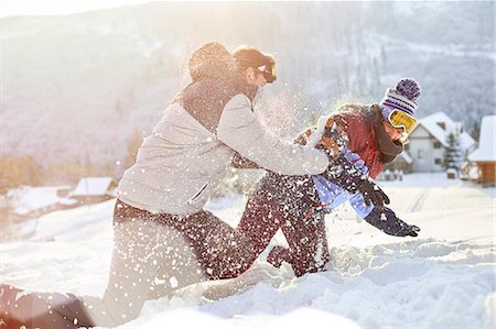 Playful couple enjoying snowball fight in snowy field Stock Photo - Premium Royalty-Free, Code: 6113-08947422