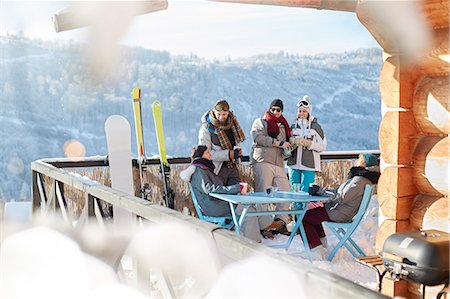 simsearch:6113-08947435,k - Skier and snowboarder couples hanging out on sunny cabin balcony apres-ski Foto de stock - Sin royalties Premium, Código: 6113-08947425