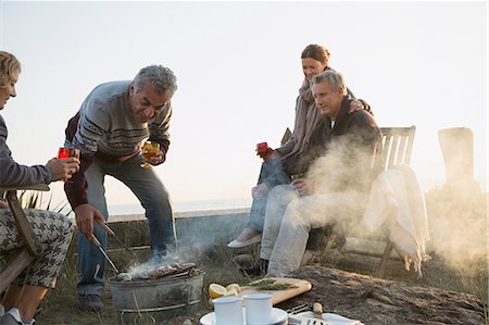Mature couples barbecuing and drinking wine on sunset beach Stock Photo - Premium Royalty-Free, Code: 6113-08985748