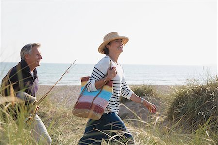 simsearch:6113-08985697,k - Mature couple with fishing rod walking in sunny beach grass Stock Photo - Premium Royalty-Free, Code: 6113-08985749