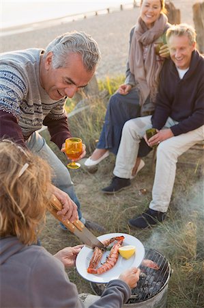 Mature couples barbecuing and drinking wine on beach Stock Photo - Premium Royalty-Free, Code: 6113-08985768