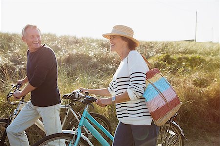 simsearch:6113-08985736,k - Mature couple walking bicycles on sunny beach grass path Stock Photo - Premium Royalty-Free, Code: 6113-08985787