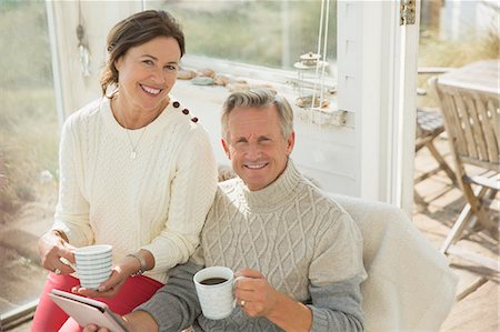 retired couple drinking coffee - Portrait smiling mature couple using digital tablet and drinking coffee on sun porch Stock Photo - Premium Royalty-Free, Code: 6113-08985788