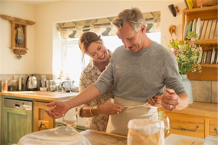 simsearch:6113-06720670,k - Playful mature couple baking, putting on apron in kitchen Foto de stock - Sin royalties Premium, Código: 6113-08985792