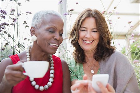 Smiling mature women friends drinking coffee and using cell phone Stock Photo - Premium Royalty-Free, Code: 6113-08985709