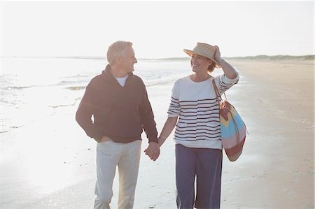 simsearch:6113-08550087,k - Smiling mature couple holding hands and walking on sunny beach Stock Photo - Premium Royalty-Free, Code: 6113-08985723