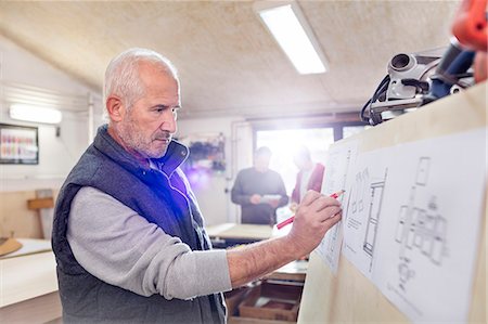Senior male carpenter editing plans in workshop Foto de stock - Sin royalties Premium, Código: 6113-08985843