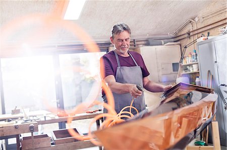 simsearch:6113-08985870,k - Male carpenter using air compressor, finishing wood kayak in workshop Stock Photo - Premium Royalty-Free, Code: 6113-08985868