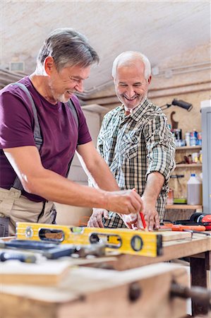 Smiling male carpenters measuring and marking wood on workbench in workshop Foto de stock - Sin royalties Premium, Código: 6113-08985877