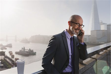 person looking down, city - Businessman talking on cell phone on sunny, urban bridge, London, UK Stock Photo - Premium Royalty-Free, Code: 6113-08985981
