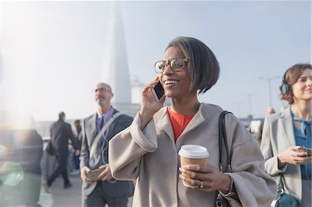 simsearch:6113-08521291,k - Smiling businesswoman drinking coffee and talking on cell phone on sunny busy urban pedestrian bridge Photographie de stock - Premium Libres de Droits, Code: 6113-08985989