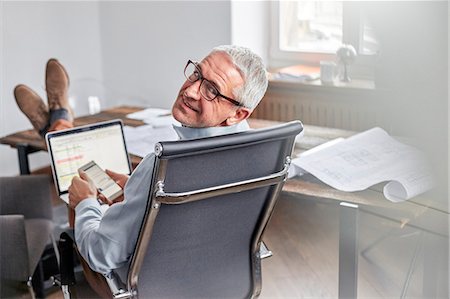 simsearch:6113-07160471,k - Portrait smiling, confident businessman with cell phone and laptop in office Stock Photo - Premium Royalty-Free, Code: 6113-08985915