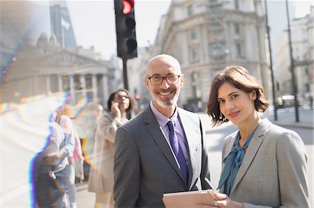 street corner london - Portrait smiling, confident business people using digital tablet on sunny urban city street, London, UK Stock Photo - Premium Royalty-Free, Code: 6113-08986047