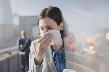 someone about to sneeze - Businesswoman with allergies blowing nose into tissue on sunny urban sidewalk Stock Photo - Premium Royalty-Free, Code: 6113-08986089