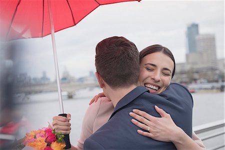 dankeschön - Smiling, affectionate couple with umbrella and flowers hugging on urban bridge, London, UK Stockbilder - Premium RF Lizenzfrei, Bildnummer: 6113-08986097