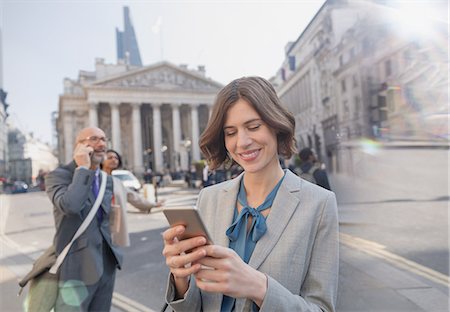 Businesswoman texting with cell phone on urban city street, London, UK Stock Photo - Premium Royalty-Free, Code: 6113-08986000