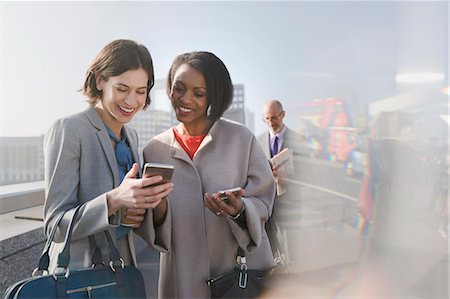 simsearch:6113-07961657,k - Smiling businesswomen using cell phone on sunny urban bridge Stock Photo - Premium Royalty-Free, Code: 6113-08986033