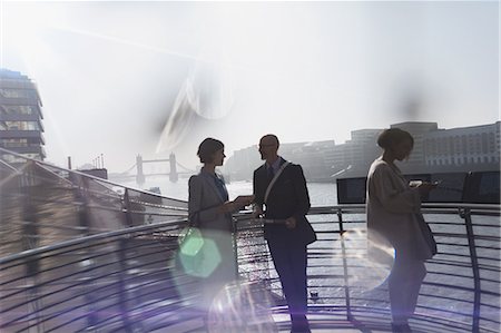 Business people with digital tablet talking on sunny boardwalk along Thames River, London, UK Stock Photo - Premium Royalty-Free, Code: 6113-08986032