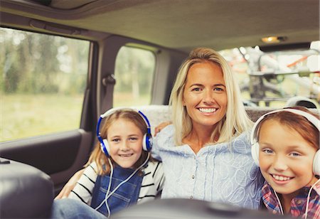 Portrait smiling mother and daughters wearing headphones in back seat of car Stock Photo - Premium Royalty-Free, Code: 6113-08909847