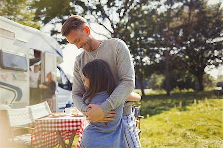 Smiling father hugging daughter outside sunny motor home Stock Photo - Premium Royalty-Free, Code: 6113-08909869
