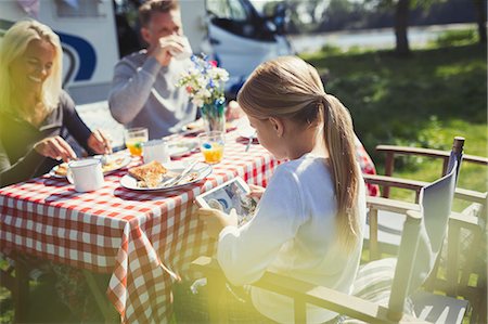 Girl using digital tablet at breakfast table outside sunny motor home Stock Photo - Premium Royalty-Free, Code: 6113-08909889