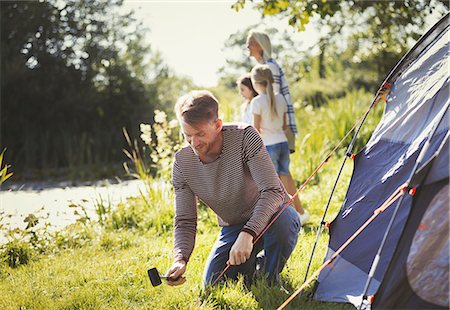 simsearch:6113-08909960,k - Father pitching tent at sunny lakeside campsite Stock Photo - Premium Royalty-Free, Code: 6113-08909956