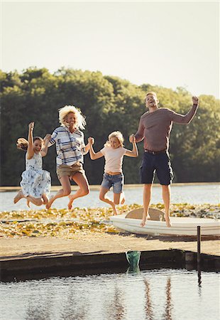 family on pier - Portrait playful family jumping on sunny lake dock Stock Photo - Premium Royalty-Free, Code: 6113-08909966