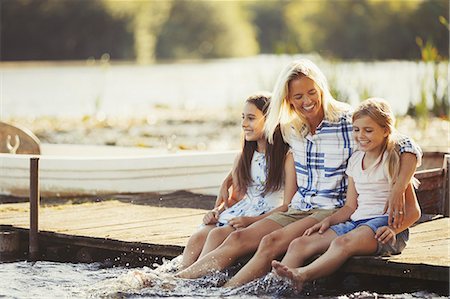 preteen kids feet - Smiling, affectionate mother and daughters on dock splashing feet in lake Stock Photo - Premium Royalty-Free, Code: 6113-08909903