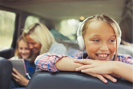 Smiling girl listening to music with headphones in back seat of car Stock Photo - Premium Royalty-Free, Code: 6113-08909916