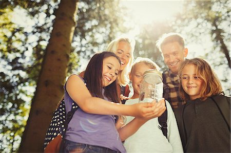 Family holding jar with butterfly in sunny woods Stock Photo - Premium Royalty-Free, Code: 6113-08909922