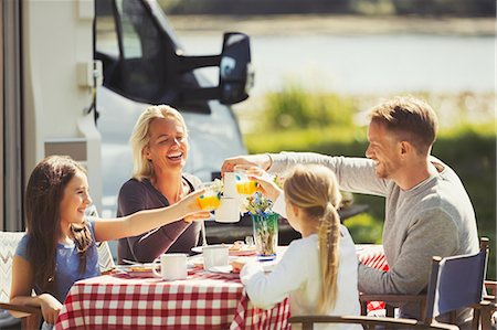 simsearch:6113-08947388,k - Family toasting coffee and orange juice glasses at table outside sunny motor home Stock Photo - Premium Royalty-Free, Code: 6113-08909935