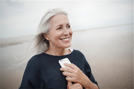 simsearch:649-08969042,k - Smiling senior woman holding cell phone on winter beach Photographie de stock - Premium Libres de Droits, Code: 6113-08910054