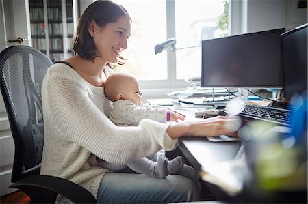 simsearch:632-03779319,k - Smiling mother holding baby daughter working at desk in home office Foto de stock - Sin royalties Premium, Código: 6113-08910065