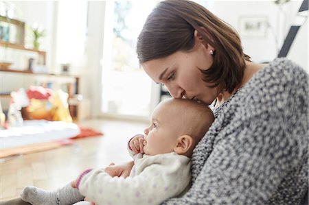 simsearch:6113-08910046,k - Mother kissing baby daughter on the head Fotografie stock - Premium Royalty-Free, Codice: 6113-08910075