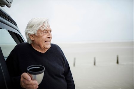 Happy senior man drinking coffee at car on winter beach Stock Photo - Premium Royalty-Free, Code: 6113-08910076