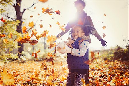 Playful mother and daughter throwing autumn leaves in sunny park Stock Photo - Premium Royalty-Free, Code: 6113-08910085