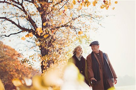 simsearch:6113-07565037,k - Affectionate senior couple holding hands walking in sunny autumn park Photographie de stock - Premium Libres de Droits, Code: 6113-08910198