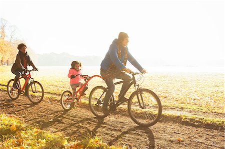 simsearch:6113-08521566,k - Young family bike riding on path in sunny autumn park Stock Photo - Premium Royalty-Free, Code: 6113-08910138