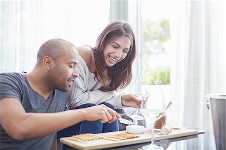 simsearch:6113-08550102,k - Smiling couple drinking white wine and eating crackers and cheese in living room Stock Photo - Premium Royalty-Free, Code: 6113-08910257