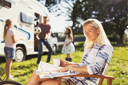 simsearch:6113-07242519,k - Smiling woman reading magazine and drinking coffee outside sunny motor home Stock Photo - Premium Royalty-Free, Code: 6113-08910261