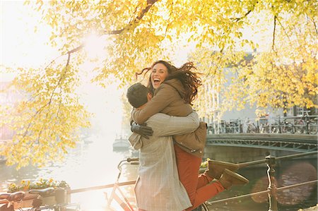 Enthusiastic couple hugging along sunny autumn canal, Amsterdam Stock Photo - Premium Royalty-Free, Code: 6113-08927683