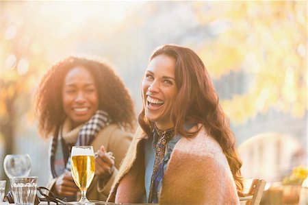 simsearch:614-06623998,k - Portrait laughing young women friends drinking beer at autumn sidewalk cafe Photographie de stock - Premium Libres de Droits, Code: 6113-08927697