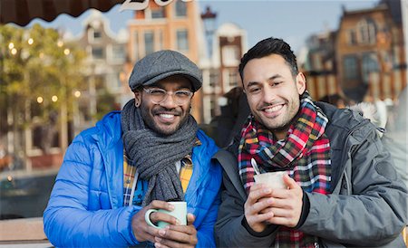 simsearch:6113-08927779,k - Portrait smiling young men friends in warm clothing drinking coffee at urban sidewalk cafe Photographie de stock - Premium Libres de Droits, Code: 6113-08927740