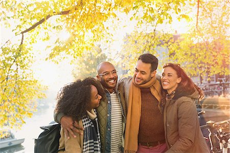 simsearch:6113-08927751,k - Smiling young friends hugging under sunny autumn tree Stock Photo - Premium Royalty-Free, Code: 6113-08927771