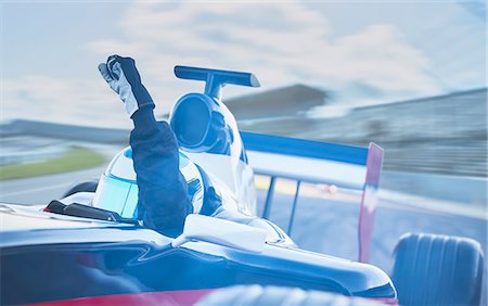simsearch:700-00071660,k - Formula one race car driver cheering, gesturing with fist on sports track Stock Photo - Premium Royalty-Free, Code: 6113-08927799