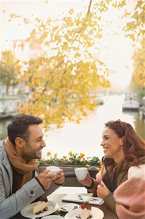 simsearch:6113-08927751,k - Young couple drinking coffee and eating cheesecake dessert at autumn sidewalk cafe along canal Stock Photo - Premium Royalty-Free, Code: 6113-08927723