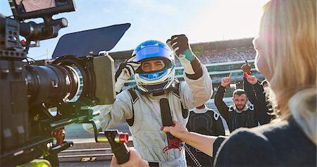 News reporter and cameraman interviewing formula one driver cheering, celebrating victory Photographie de stock - Premium Libres de Droits, Code: 6113-08927849